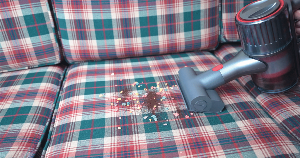 cordless vacuum in handheld mode vacuuming upholstery.