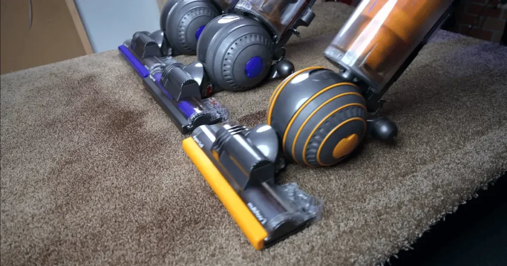 Three upright Dyson Vacuums on Carpet.