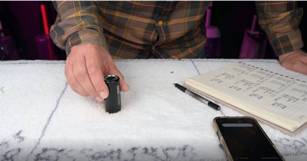 A colorimeter measuring the lightness of a dried stain sample on a test surface to determine cleaning effectiveness.