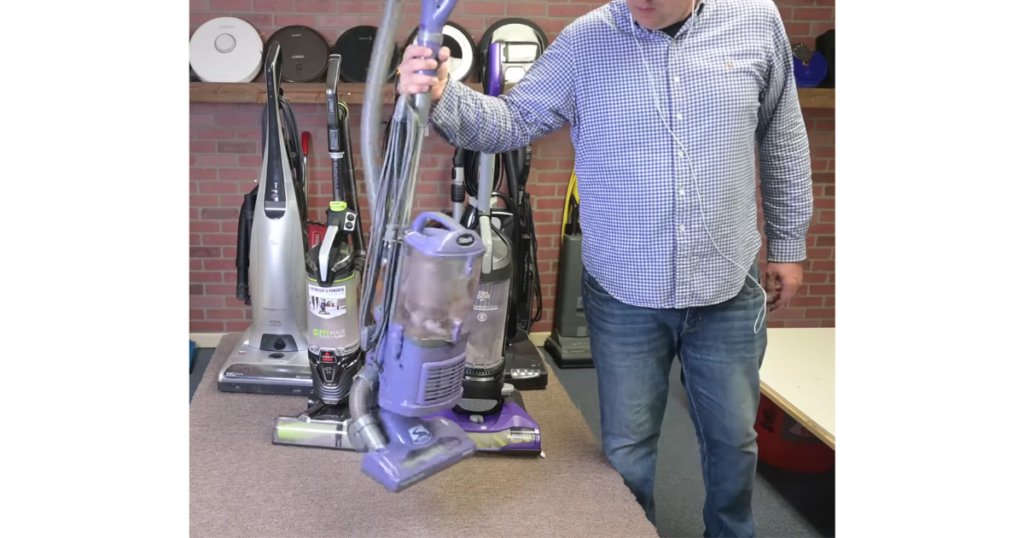 Holding up a lightweight upright vacuum with one hand.