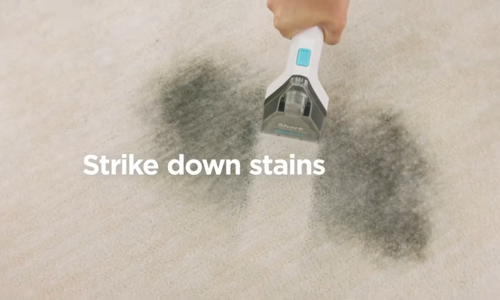 Handheld attachment of the Shark CarpetXpert EX201 being used on a carpet to remove a concentrated stain.