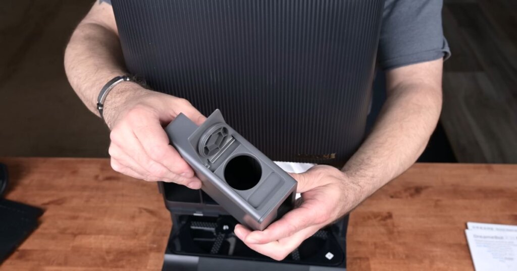 Close-up of a person holding the Dreame X30 Ultra’s universal detergent tank module for the dock.
