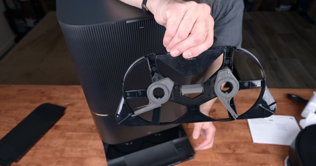 A hand holds the underside of Dreame X30 Ultra’s auto-cleaning dock component, showing scrubbing mechanisms.