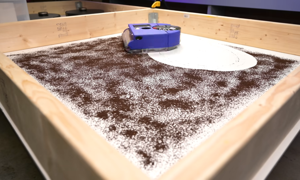 Dyson 360 Vis Nav robot vacuum performing a cleaning evaluation on a carpet heavily laden with brown debris, demonstrating its suction power.