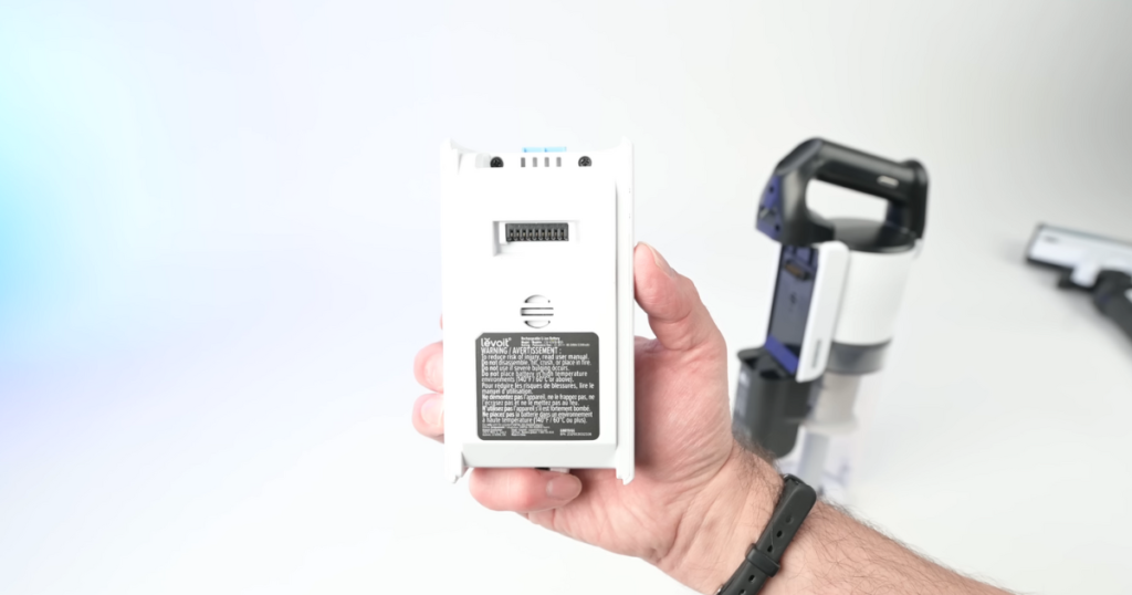 Close-up view of a hand holding a removable battery pack from the Levoit LVAC-200 cordless vacuum.