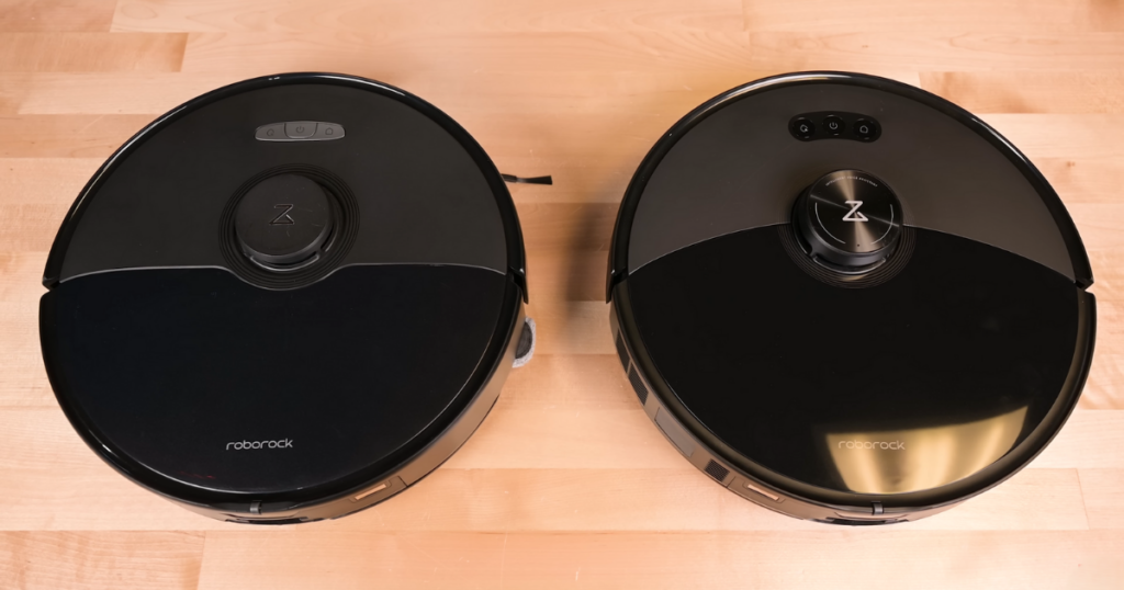 Top view of two Roborock robot vacuums placed side by side on a wooden surface. The vacuum on the left is the Roborock S8 Max Ultra, and the vacuum on the right is the Roborock S8 MaxV Ultra. 