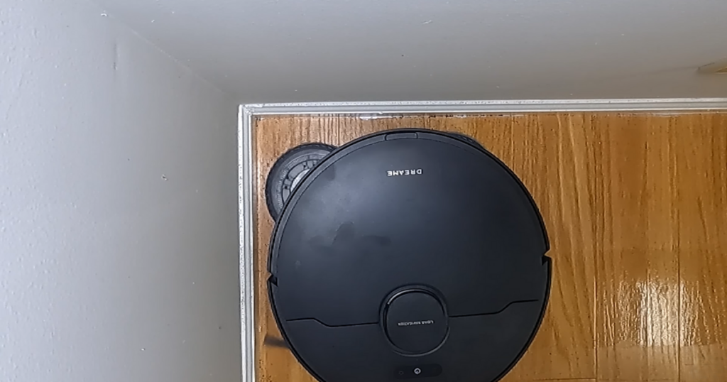 Top view of the Dreame X40 Ultra robot vacuum cleaning a corner of a hardwood floor.