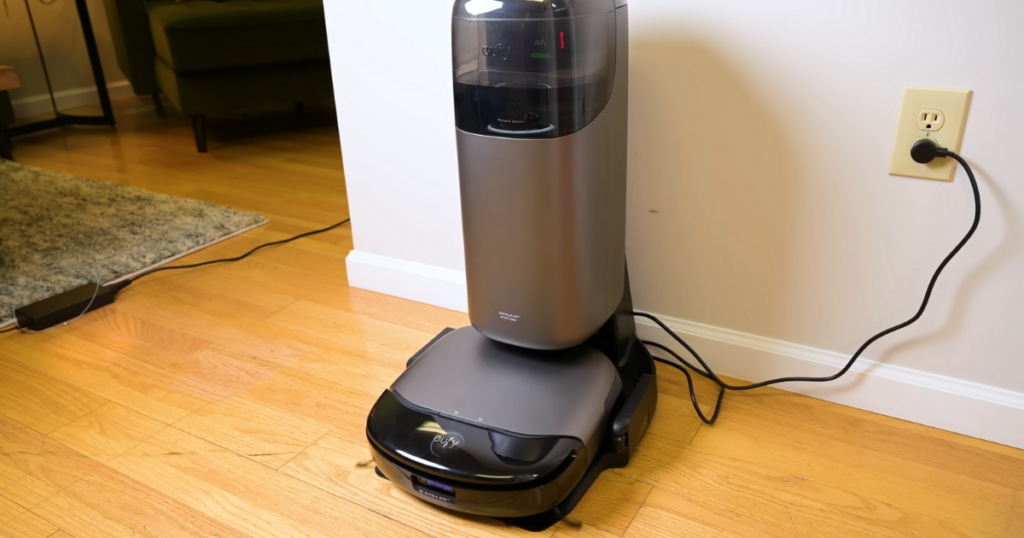 Eufy S1 Pro Omni robot vacuum and UniClean Station plugged in and positioned against a wall on a hardwood floor.