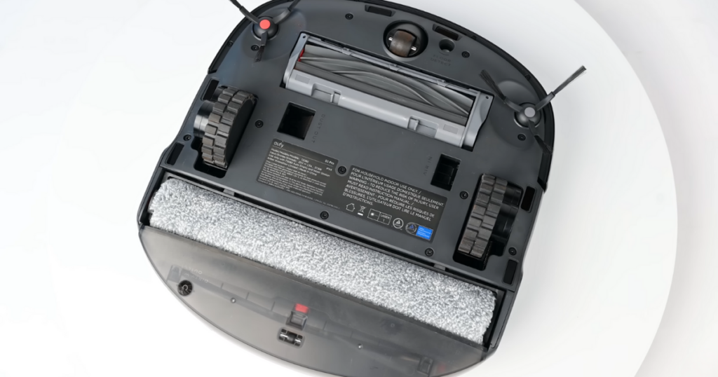 Bottom view of the Eufy S1 Pro Omni robot vacuum showcasing its roller brush, wheels, side brushes, and mopping system.