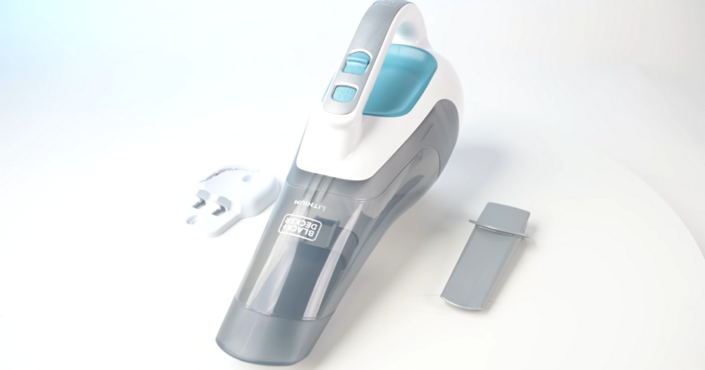 A Black+Decker HHV1315J042 handheld vacuum in gray and white with a blue handle, accompanied by a wall mount and a crevice tool, placed on a white surface.