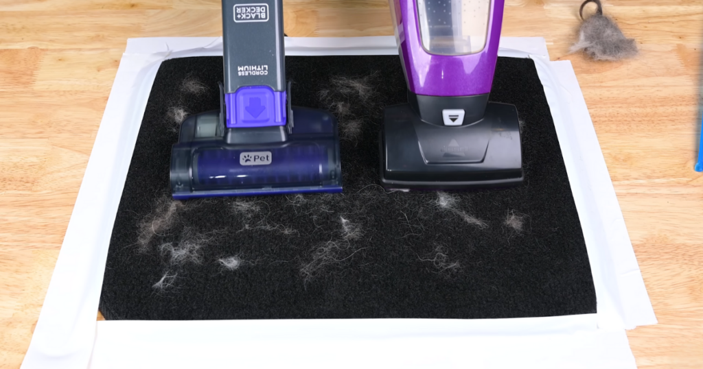 Two handheld vacuums on a black carpet, demonstrating their effectiveness at picking up pet hair. The vacuum on the left has a motorized pet attachment.