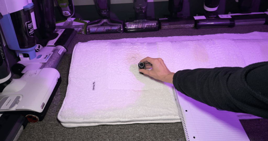 Technician measuring carpet stain lightness with a handheld colorimeter after the carpet has fully dried.