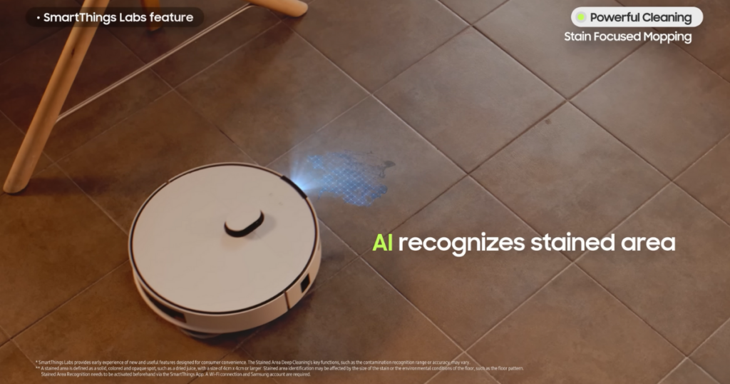 A Samsung Bespoke Jet Bot Combo AI robot vacuum using its AI to recognize a stained area on a tiled floor, with a blue light highlighting the spot for targeted cleaning.