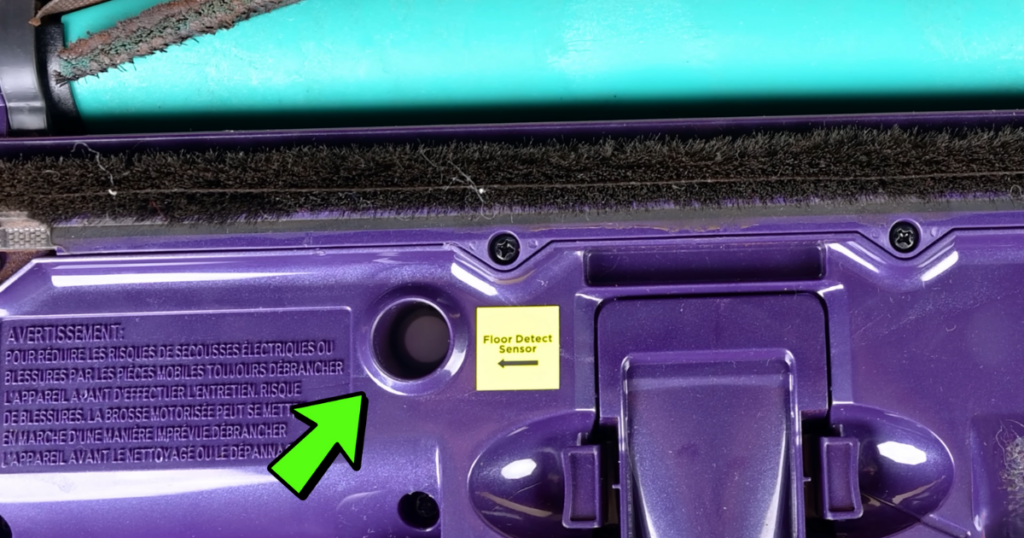 Close-up view of the Shark PowerDetect vacuum's floor detect sensor, located near the DuoClean roller. A green arrow points to the sensor, which is labeled with a yellow sticker.