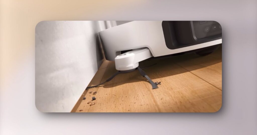 Close-up of Dreame L40 Ultra using its extending side brush to clean debris from the edge of a floor along a wall.