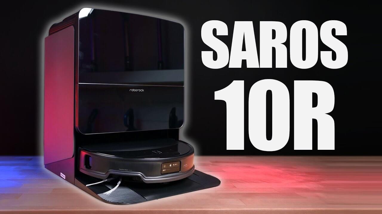 The Roborock Saros 10R robot vacuum docked at its base, with a glossy black finish and illuminated ambient lighting.