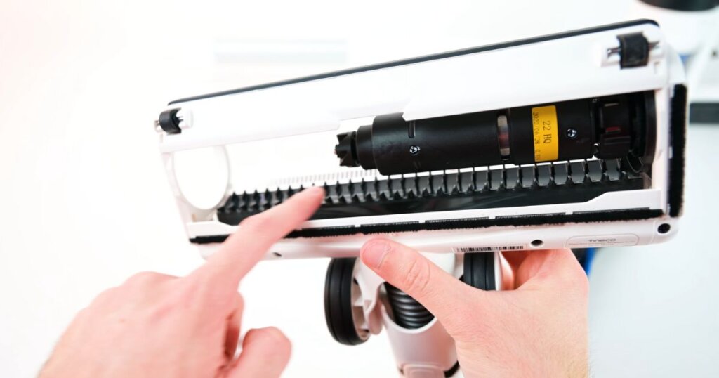 Close-up of a vacuum cleaner head with active hair removal combs built into the brush housing.