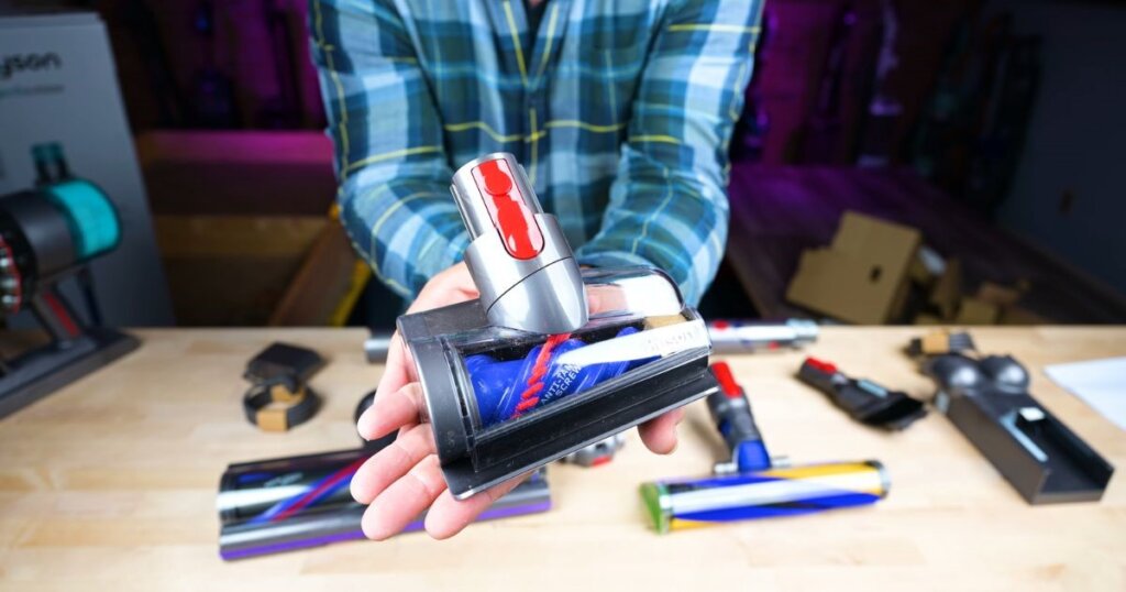 Person holding a small motorized vacuum brush attachment with a visible spinning brushroll.