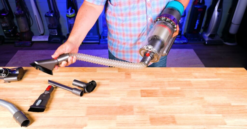 Person using a third-party flexible hose attachment on a Dyson cordless vacuum for handheld cleaning.