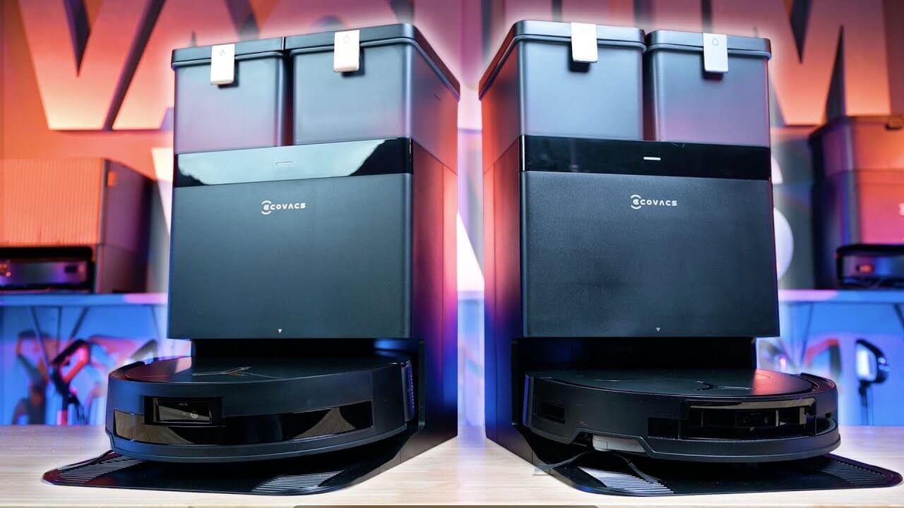 Front view of the Ecovacs T50 Max Pro Omni and T50 Pro Omni robot vacuums docked in their base stations, side by side on a wood surface under studio lights.