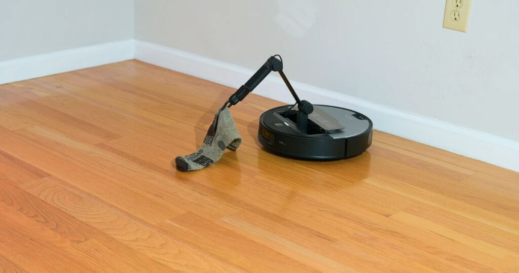 Roborock Z70 using its mechanical Omni-Grip arm to pick up a sock during testing.