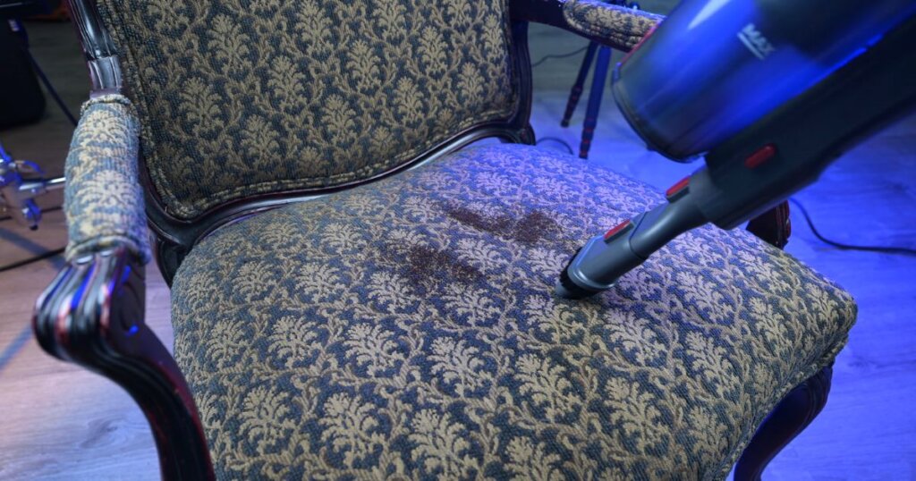 Smoture VAC01 being used in handheld mode to clean dirt from an upholstered chair.