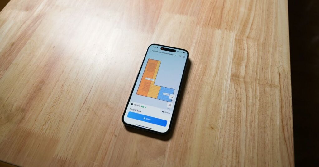 Smartphone displaying the Ecovacs app interface, showing mapped rooms with cleaning zones and an option to start the T50 Max Pro Omni.