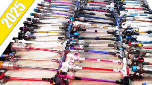 Top-down view of dozens of cordless vacuums laid out in rows, showing a wide variety of brands and models.