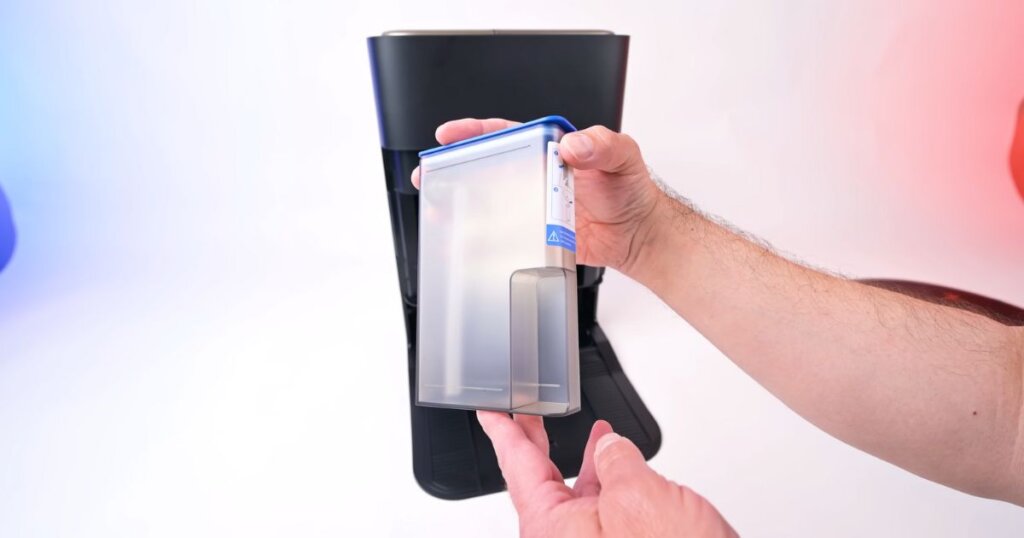 Close-up of a hand holding the clear detergent reservoir from the Ecovacs X9 Pro Omni dock.
