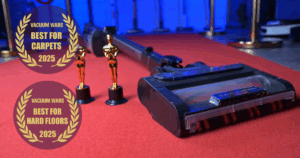 Shark Stratos cordless vacuum on a red carpet beside two trophy statues, with badges reading "Best for Carpets 2025" and "Best for Hard Floors 2025" from Vacuum Wars.