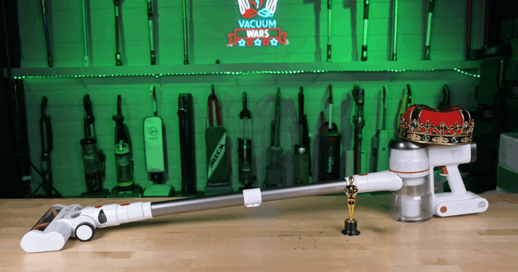 Tikom V500 cordless vacuum placed on a table with a miniature trophy and a royal crown at the Vacuum Wars studio.