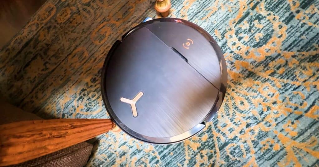 Ecovacs X9 Omni robot vacuum wedged against a table leg during operation on a patterned rug.