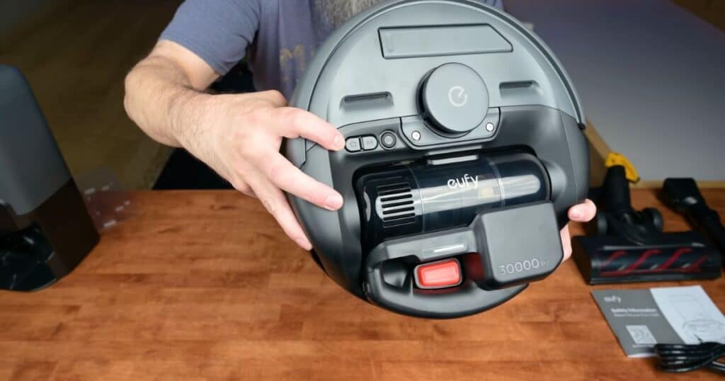 Close-up of the Eufy E20 robot vacuum underside showing the detachable cordless vacuum unit with red release button.