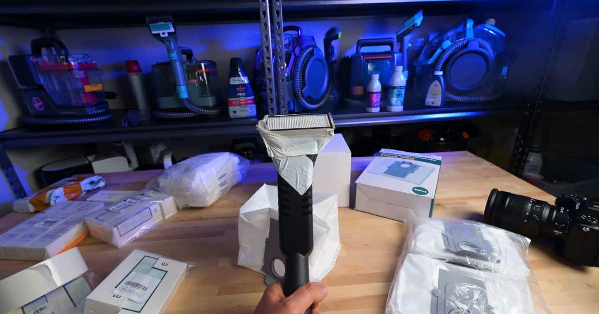 A handheld vacuum with a taped filter attachment prepared for fog testing against off-brand filters in a controlled environment.