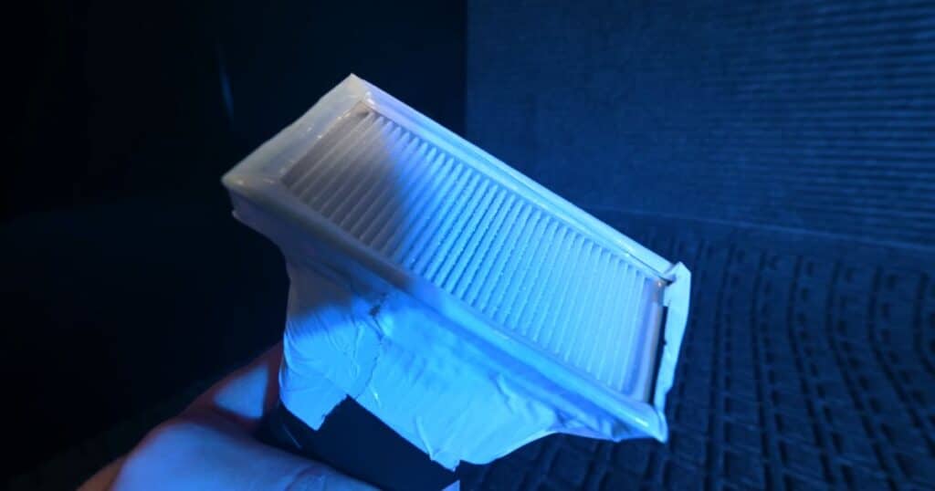 Official Roborock filter held under blue light after fog evaluation, showing no visible fog leakage through the filter.
