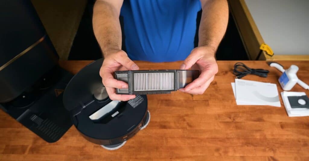 Person holding the Dreame L50 Ultra robot vacuum’s rectangular dust bin with filter visible.