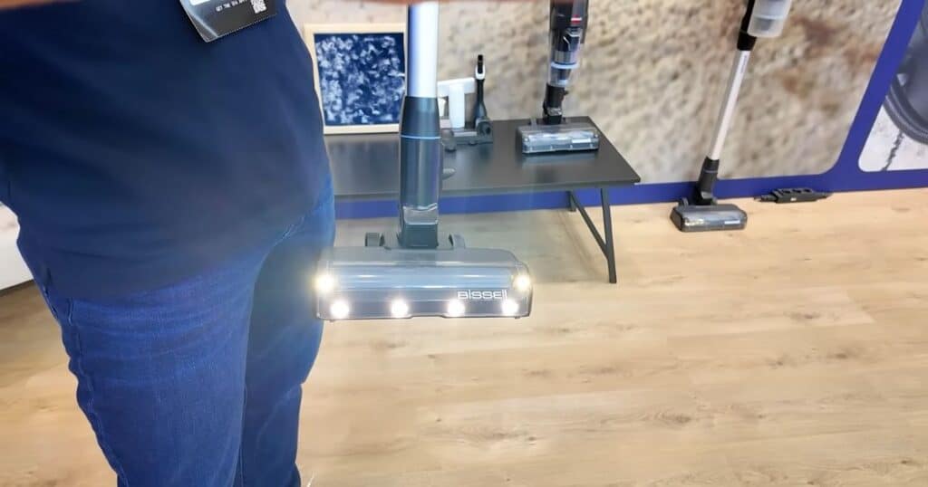 Close-up of the Bissell PowerClean FurGuard vacuum head showing four bright LED headlights illuminated at IFA 2025.