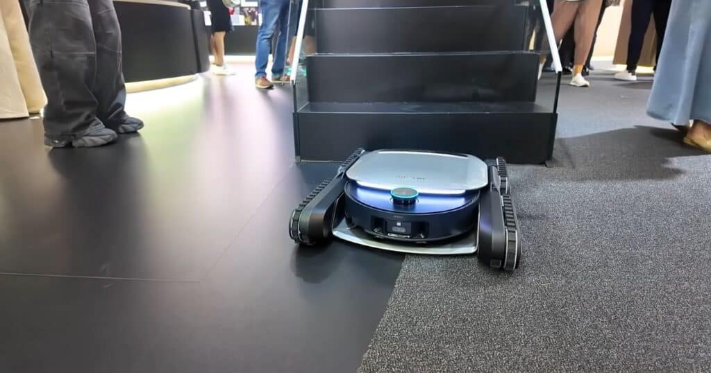 Dreame stair-climbing robot vacuum prototype at IFA 2025 using rubber tracks positioned in front of a staircase.