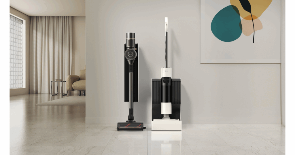 LG Stick Vacuum | Vacuum Wars Two LG cordless stick vacuums, one black and one white, standing upright on matching freestanding charging bases in a minimalist living room with light floors and abstract wall art.