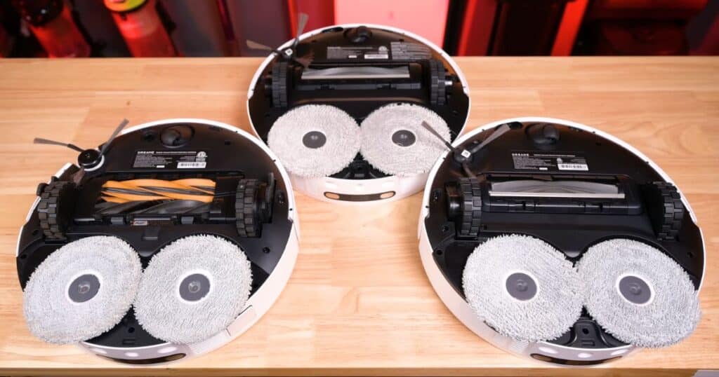 Underside view of three Dreame robot vacuums showing dual spinning mop pads and brush rollers, highlighting differences across the L40s lineup.
