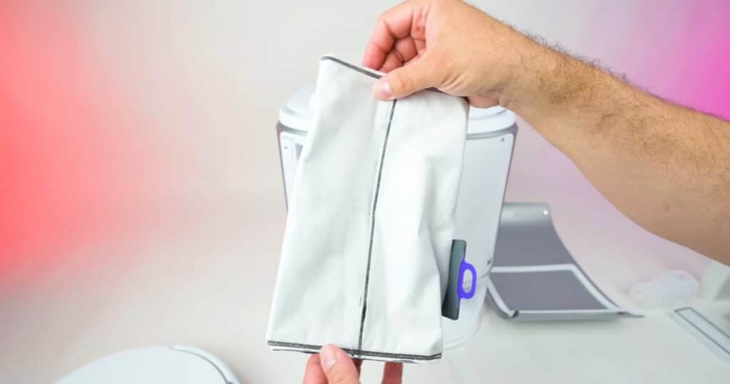 Close-up of a hand holding the Narwal Flow’s white disposable dust-collection bag.
