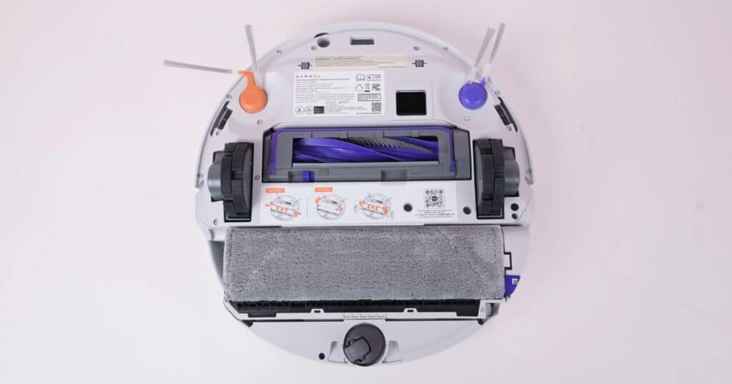 Underside view of the Narwal Flow robot vacuum showing dual side brushes, main brush roll, and roller-style mop pad assembly.