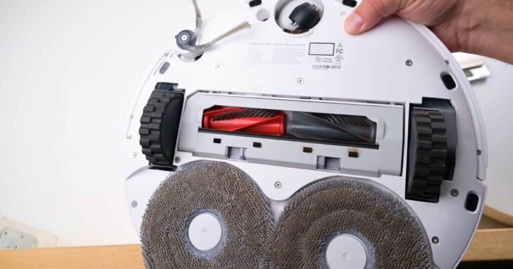 Underside of Roborock Qrevo CurvX showing dual mop pads, DuoDivide main brush, side brush, and wheel assembly.