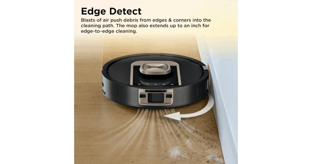 Shark PowerDetect ThermaCharged robot vacuum cleaning along a wall, using Edge Detect technology to pull debris away from baseboards and into its suction path.