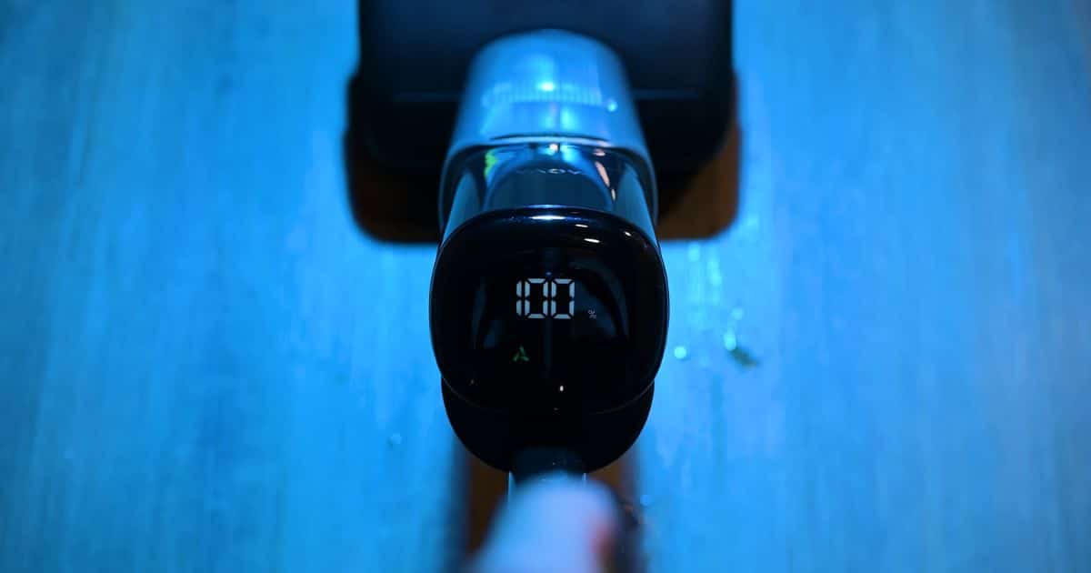 A top-down view of a hard floor cleaner handle showing an illuminated digital display with the battery at 100 percent.