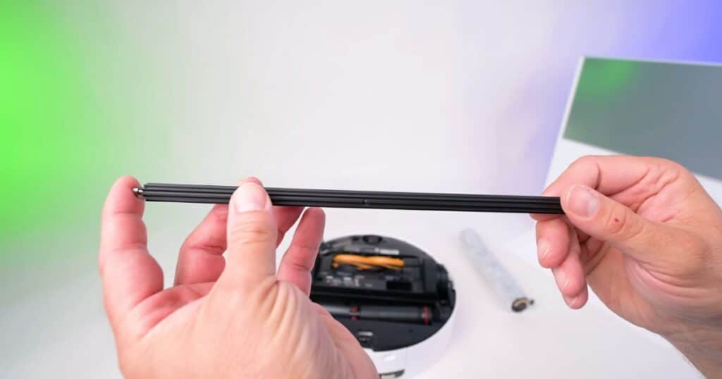 | Vacuum Wars Close-up of a person holding the Dreame Aqua 10 Ultra Roller’s secondary FluffRoll Tech module, a slim rotating component designed to maintain roller fiber shape and improve long-term mopping performance.