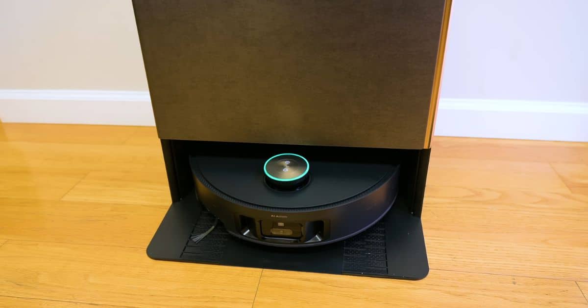 Close-up photo of the Dreame Matrix10 Ultra docked in its base on a hardwood floor, with the circular LiDAR turret on top lit by a green ring as the robot rests on the ramp.