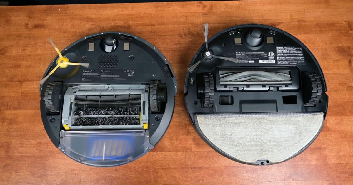 | Vacuum Wars Top-down view of the undersides of two robot vacuums on a wood surface used for our MOVA S10 review: the Roomba 600 series on the left with dual brush rolls and a yellow side brush, and the MOVA S10 on the right with a single rubber main brush, side brush, and an attached mopping pad.
