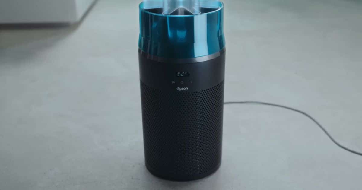 | Vacuum Wars Dyson HushJet Purifier Compact on a light-colored floor, showing a cylindrical body with a perforated base and a blue transparent top.