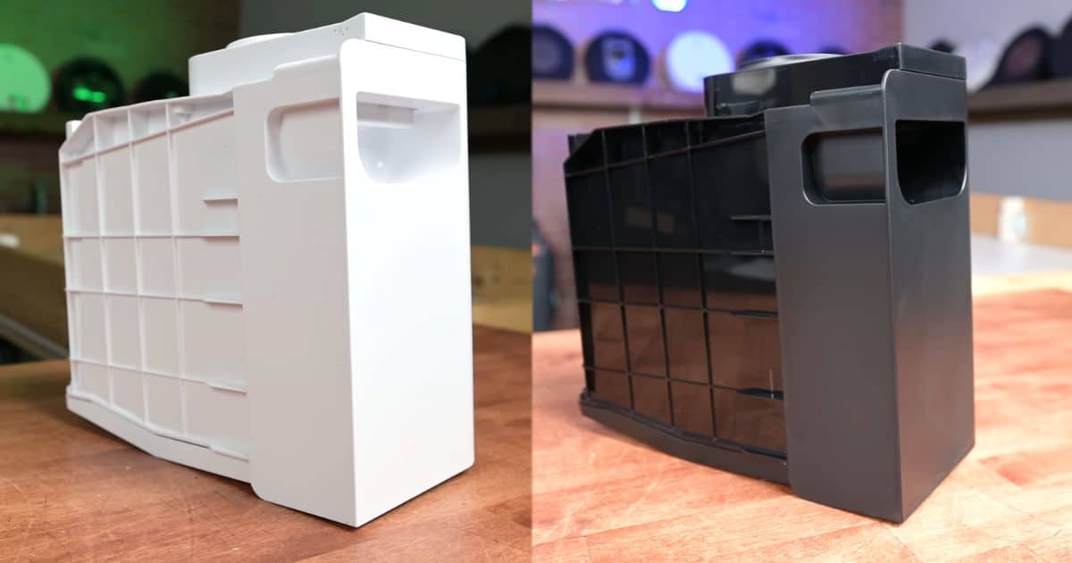| Vacuum Wars Side-by-side photo of two removable bagless dock bins belonging to the PowerDetect ThermaCharged and PowerDetect NeverTouch Pro. One white bin and one dark gray bin, shown on a tabletop.